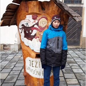 Žák před dřevěnou schránkou Ježíškovi vánoční pošty